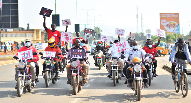 Youth from Crime Si Poa affiliate groups on motorcycles holding up signboards with anti-crime messages 