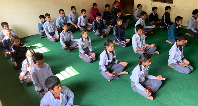 A group of school children practicing yoga and meditation.